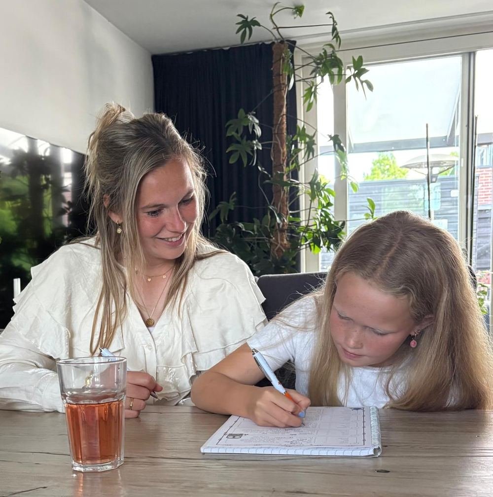 Monique helpt een leerling met een rekenopgave aan de keukentafel